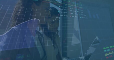 Leaning colleagues in business attire reading finance charts at window, with laptop and overlays