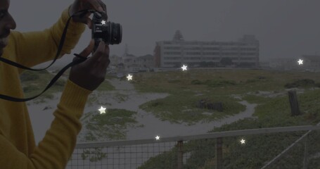 Holding DSLR camera, man in mustard sweater shooting coastal dunes on platform railing, copy space