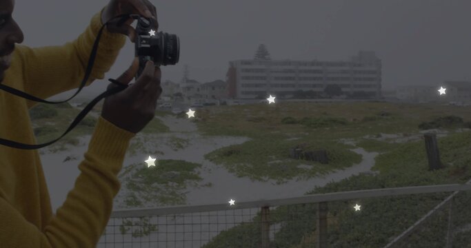 Holding DSLR camera, man in mustard sweater shooting coastal dunes on platform railing, copy space - Powered by Adobe