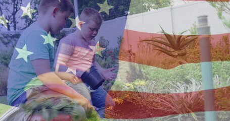 Kneeling brothers holding black plastic pot while scooping soil in backyard, succulent shrubs