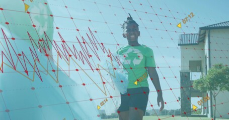 Walking boy in green recycling tee carrying bagged bottle under red grid across yard, copy space