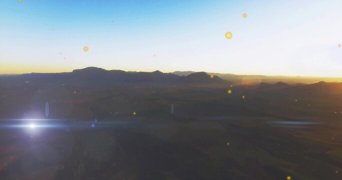 Fototapeta Showing dark mountain ridge against bright sunrise horizon, with valley textures and lens flare
