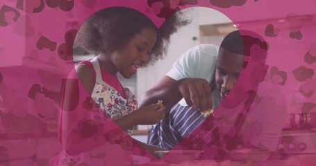 Mixing father and daughter adding small ingredient pieces into mixing bowl in home kitchen, aprons