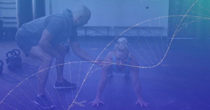 Trainee holding push-up position on mat at gym, trainer guiding form with kettlebells weight rack