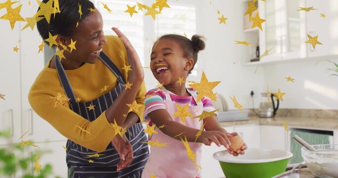 Baking mother and daughter raising high-five hands in modern home kitchen, with green mixing bowl - Powered by Adobe