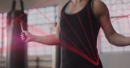 Gripping jump rope handles, woman in sportswear jumping at gym with punching bags, red dotted lines