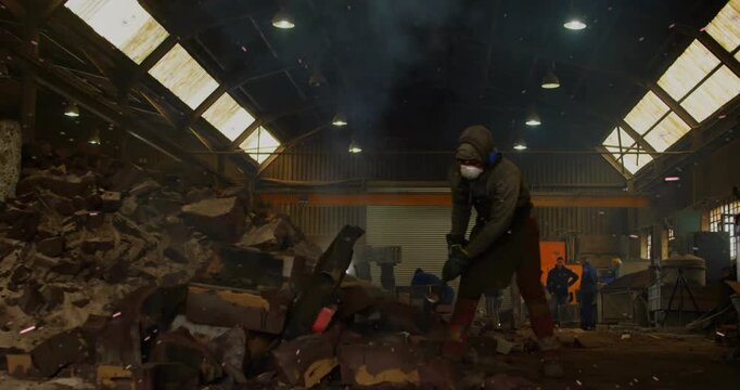 Laborer raising sledgehammer, breaking scrap for metal recycling workshop, sending sparks flying