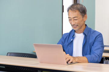 ノートパソコンを使うシニア男性