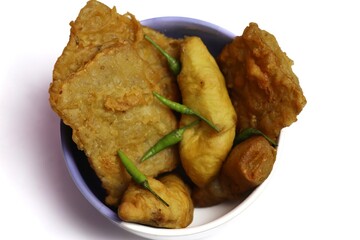 A delicious Indonesian fried dish featuring crispy tempeh mendoan and fried tofu served warm in a white bowl, topped with fresh green chilies for a spicy finish