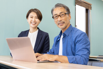 パソコン教室に通うシニアと教える講師