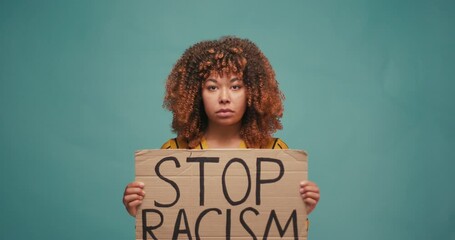 Hispanic Woman hold poster Stop Racism look at camera serious racial morality society peace matter human text words can kill torture close up slow motion