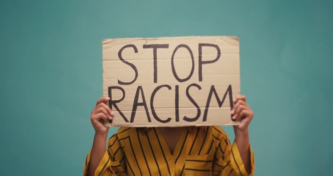 Hispanic Woman hold poster Stop Racism look at camera serious racial morality society peace matter human text words can kill torture close up slow motion