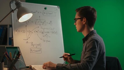 Young man solving complex math equations on whiteboard in home office with green screen - Powered by Adobe