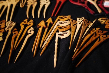 Handmade wooden hairpins with carved ornaments lying on black velvet background for sale at craft...