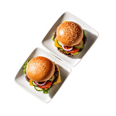 Two gourmet American burgers with sesame seed buns, cheese, lettuce, tomato, cucumber, and onion, presented on square ceramic plates from a top-down view.

