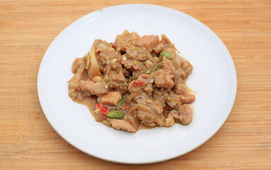 Stir-fried pork with shrimp paste and stink bean in white plate on bamboo wooden board background.