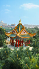 Naklejka premium Traditional Chinese temple in Penglai, Shandong, with red pillars, golden roofs, and ornate details, surrounded by lush greenery and a serene natural setting.