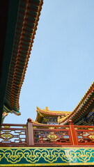 Obraz premium Traditional Chinese temple in Penglai, Shandong, with red pillars, golden roofs, and ornate details, surrounded by lush greenery and a serene natural setting.