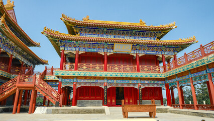 Traditional Chinese temple in Penglai, Shandong, with red pillars, golden roofs, and ornate details, surrounded by lush greenery and a serene natural setting.