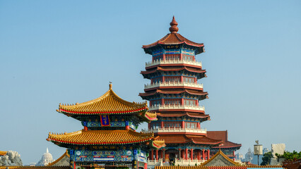 Traditional Chinese temple in Penglai, Shandong, with red pillars, golden roofs, and ornate details, surrounded by lush greenery and a serene natural setting.