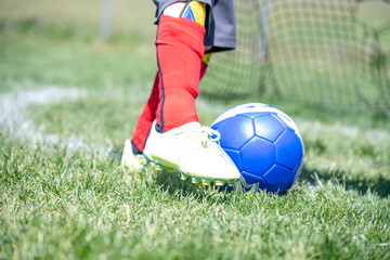 Youth soccer player prepares to kick a ball into the net on a sunny day at a local sports field