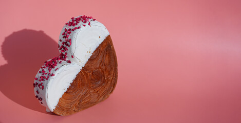 Heart shaped white chocolate croissant on pink background with copy space. Puff pastry new trendy...