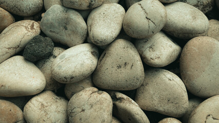 Smooth pebbles background featuring a variety of natural stones in different shapes, colors, and...