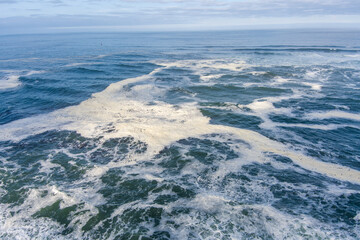 Seascape of the Pacific Ocean along the Oregon coast on an overcast cloudy day with crashing waves  and foamy seas