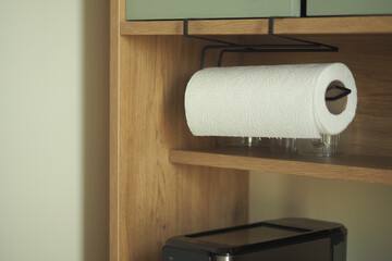 Paper towel holder on a wooden shelf in a kitchen