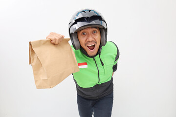 Excited Asian online driver standing while carrying a package with funny face expression
