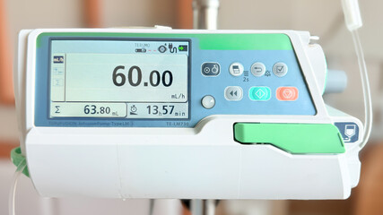 Medical infusion pump with digital screen displaying flow rate in a hospital room. Pediatric patient resting in bed in the background. Healthcare and intravenous therapy concept.