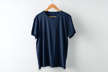 Dark Blue T-Shirt Hanging on a Wooden Hanger Against a White Wall.