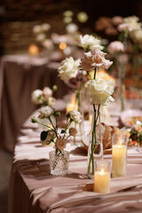 Wedding banquet table decorated with flowers, candles and food in festive hall with dark background. Concept of celebration, romance, event decoration, reception.