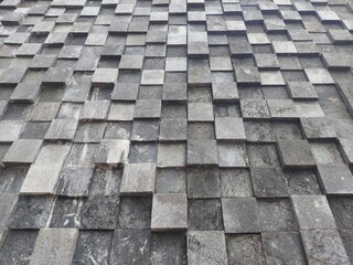 Close-up of a gray stone wall with 3D square block texture.