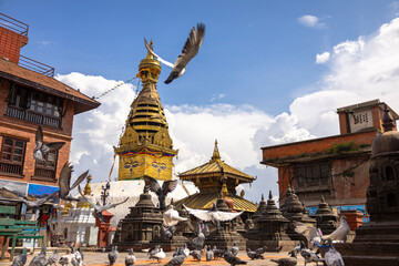 Pigeons flying around Swayambhunath Stupa (Monkey Temple) in Kathmandu, Nepal, with traditional architecture and dramatic skies. A spiritual and cultural landmark of Himalayan heritage.