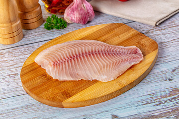 Raw tilapia fish fillet over board