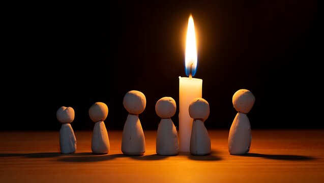 Wooden figures surrounding lit candle against dark background concept
