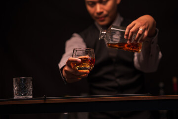 Business man bartender pours whiskey into a glass, sitting sadly in a restaurant	