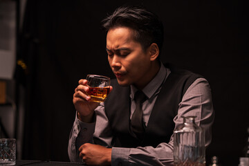 Business man bartender pours whiskey into a glass, sitting sadly in a restaurant	