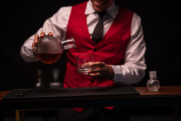 Bartender is pouring whiskey into a glass in a restaurant
