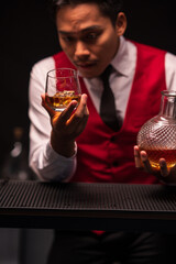 Bartender is pouring whiskey into a glass in a restaurant