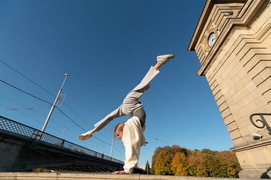 Young woman performing a handstand split in an urban setting
