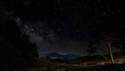 Night Sky with Milky Way Galaxy over Dark Landscape with Trees and Distant Mountains Under the Starry Sky and Clouds in the Horizon