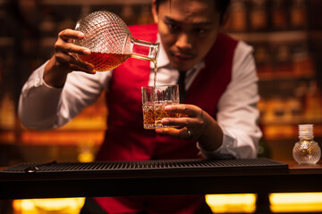 Business man bartender pours whiskey into a glass, sitting sadly in a restaurant	