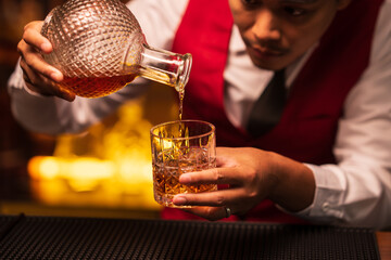 Business man bartender pours whiskey into a glass, sitting sadly in a restaurant	