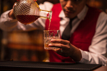Bartender is pouring whiskey into a glass in a restaurant	
