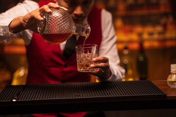 Bartender is pouring whiskey into a glass in a restaurant	