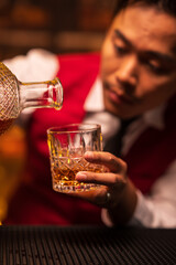 Bartender is pouring whiskey into a glass in a restaurant