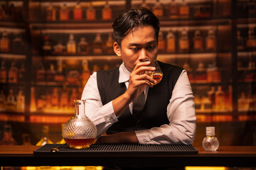 Business man bartender pours whiskey into a glass, sitting sadly in a restaurant
