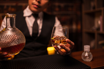 Business man bartender pours whiskey into a glass, sitting sadly in a restaurant